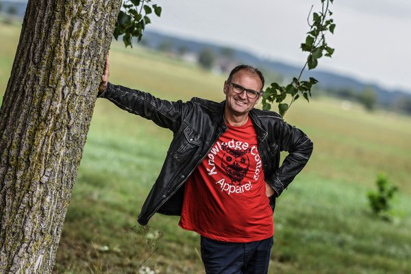 Mann lehnt sich an einen Baum.