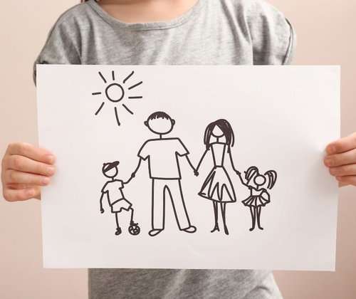 Kind zeigt eine Zeichnung mit einer Familie 