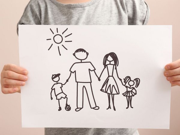 Kind zeigt eine Zeichnung mit einer Familie 