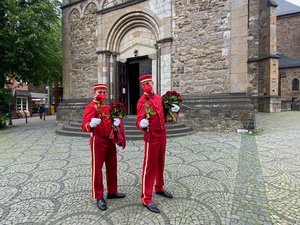 Zwei Männer in roten Portiersanzügen verteilen Rosen.