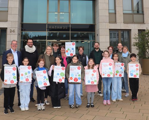 Gruppenbild mit Erwachsenen und Kindern, diese halten Schilder in die Höhe 
