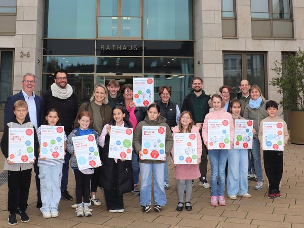 Gruppenbild mit Erwachsenen und Kindern, diese halten Schilder in die Höhe 
