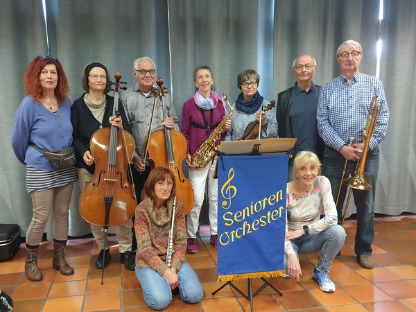 Mehrere ältere Personen mit Musikinstrumenten auf einer Bühne 