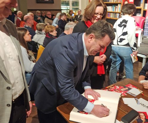 Mann beugt sich über großes Buch und schreibt 