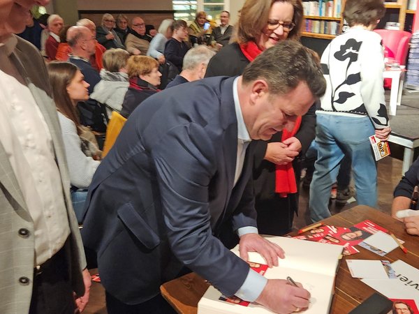 Mann beugt sich über großes Buch und schreibt 
