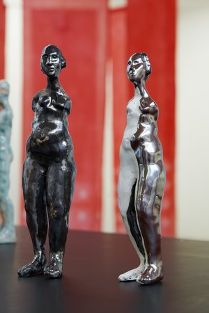 Zwei weiblich gelesene Frauenfiguren aus Ton, teilweise dunkel lasiert