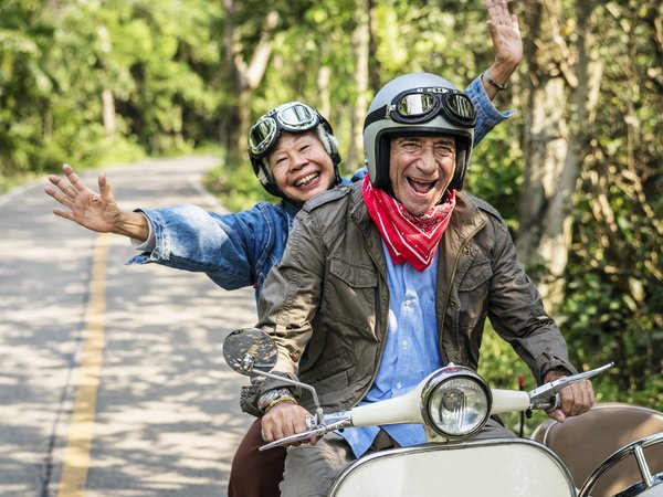 Älterer Mann und ältere Frau gut gelaunt auf einem Motorrad
