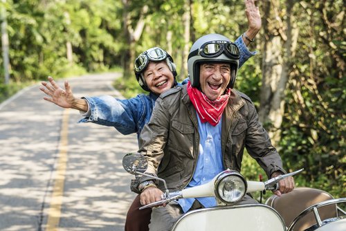 Älterer Mann und ältere Frau gut gelaunt auf einem Motorrad