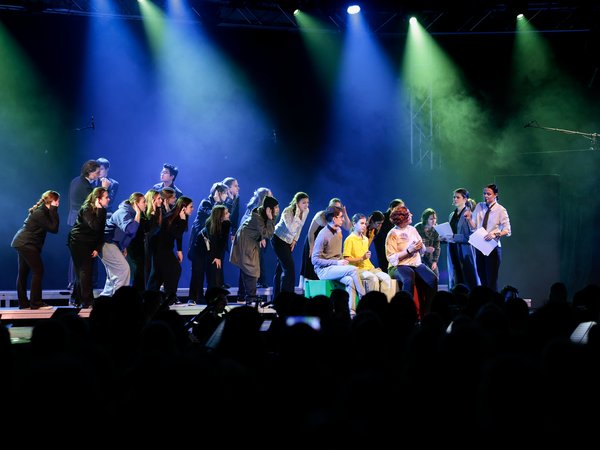 Viele junge Menschen singend und tanzend auf einer Theaterbühne