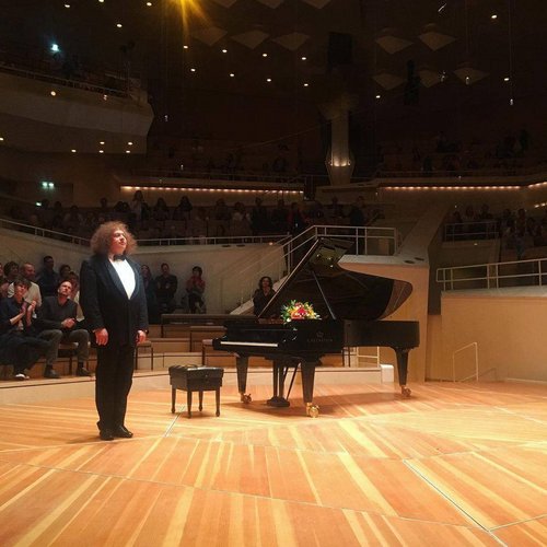 Mann steht auf Bühne neben Klavier