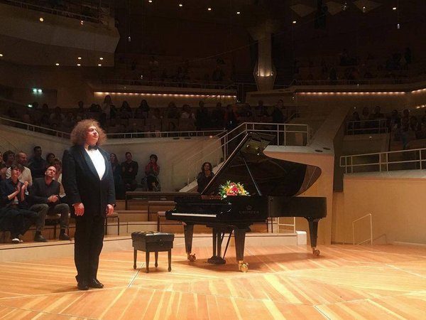 Mann steht auf Bühne neben Klavier