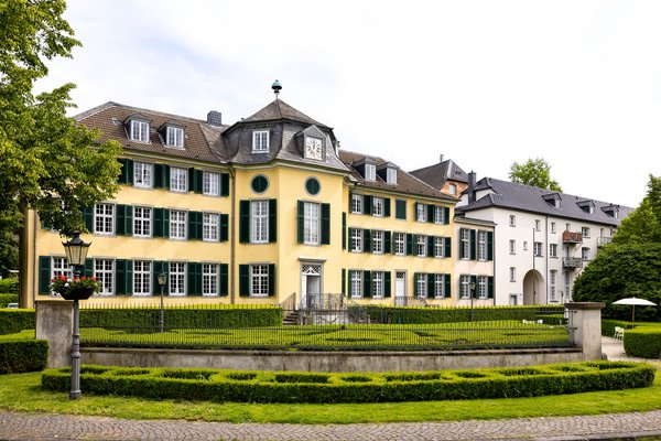Außenansicht des Herrenhauses Cromford mit Garten und dem daneben stehenden Museum
