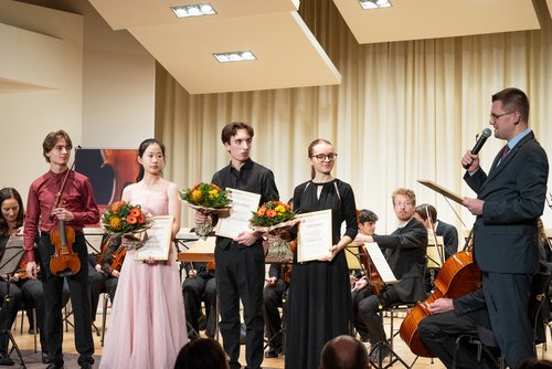 Mehrere Personen mit Urkunden auf einer Bühne 