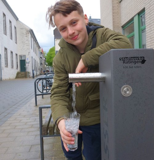 Ein Junge füllt sich Wasser in ein Glas