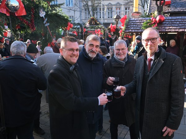 Weihnachtsmarkt Eröffnung: Vier Männer stoßen mit Glühwein an