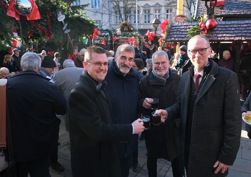 Weihnachtsmarkt Eröffnung: Vier Männer stoßen mit Glühwein an