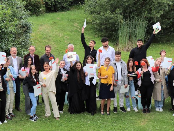 Gruppenfoto, mehrere Personen halten Blumen und Zeugnisse in den Händen