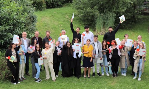 Gruppenfoto, mehrere Personen halten Blumen und Zeugnisse in den Händen