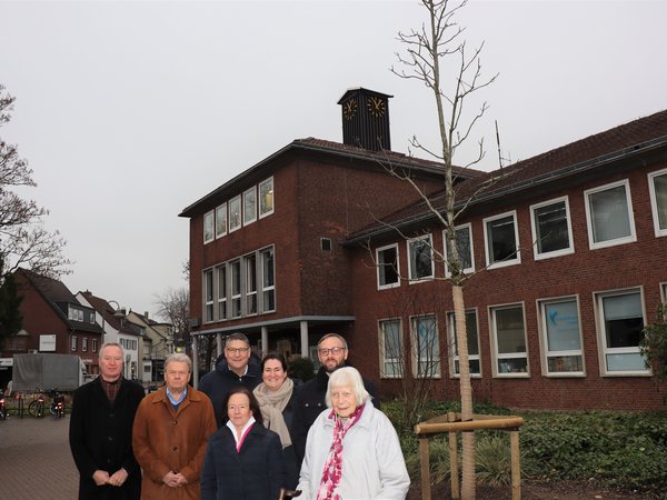 Personengruppe vor einem Jungbaum, im Hintergrund das alte Lintorfer Rathaus