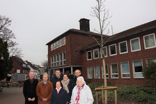 Personengruppe vor einem Jungbaum, im Hintergrund das alte Lintorfer Rathaus