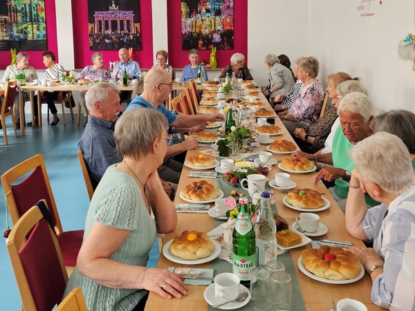 Mehrere Personen sitzen an der gedeckten Café-Tafel