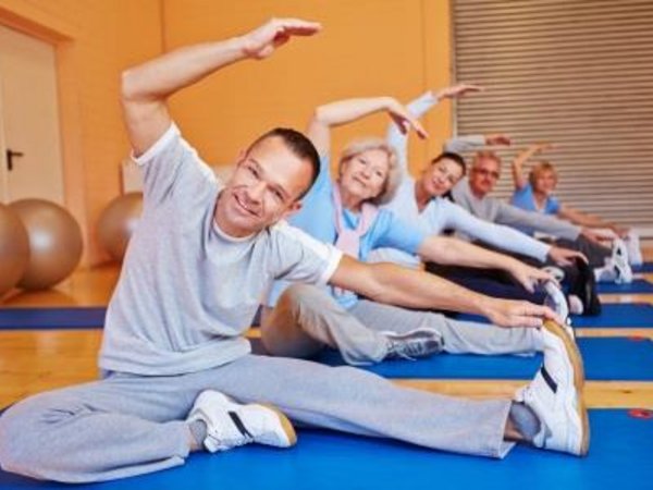 Mehrere Personen auf Gymnastikmatten bei einer Dehnungsübung