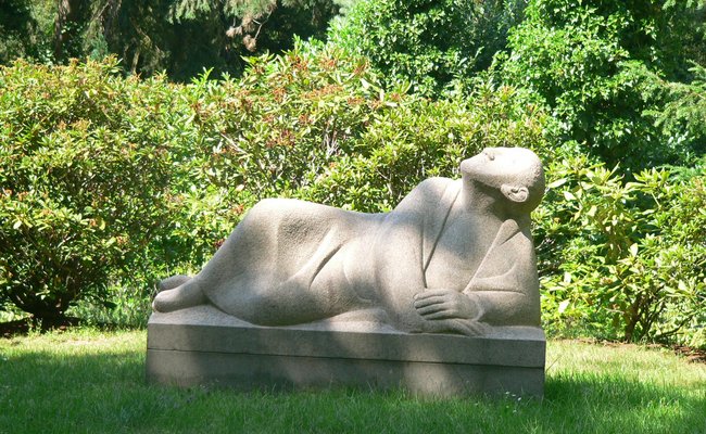 Staue einer liegenden Person, die den Blick in den Himmel richtet