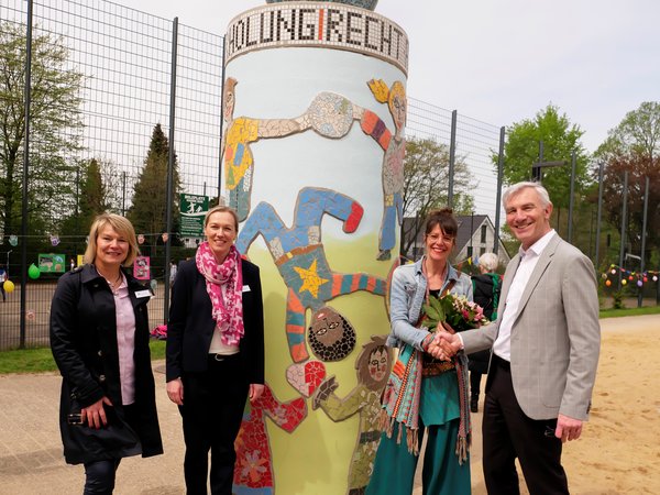 Vier Personen an einer Mosaik-Litfaßsäule