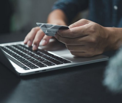 Mann mit Bankkarte vor einem Laptop