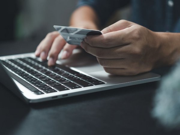 Mann mit Bankkarte vor einem Laptop