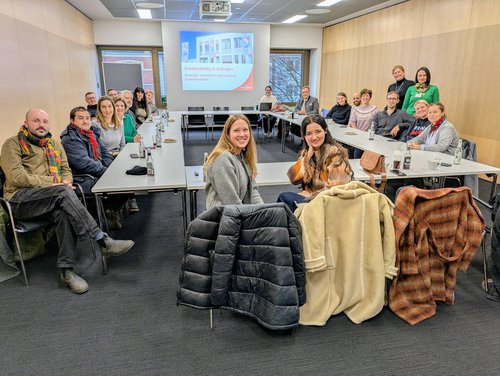 Mehrere Personen sitzen um einen Tisch herum