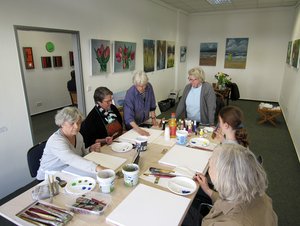 Eine Gruppe von Senioren und Kindern arbeiten an einem Kunstprojekt. 