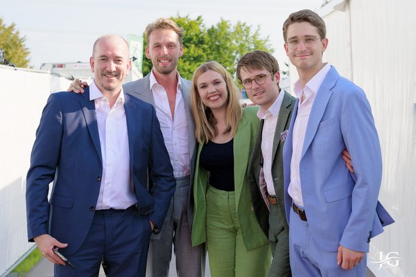 6 Personen stehen Arm in Arm als Gruppe.