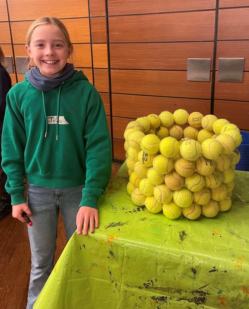 Mädchen steht neben einem Tisch aus Tennisbällen