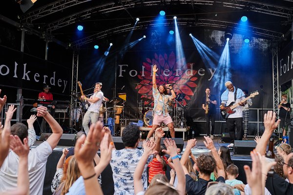 Jubelnde Menge vor einer Bühne, auf der eine Band spielt