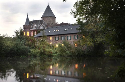 Außenansicht eines Schlosses, davor ein Gewässer 