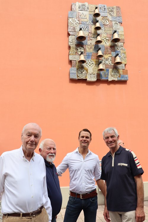 Mehrere Personen vor einem Glockenspiel an einer Hauswand.