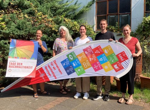 Fünf Personen halten Plakate und Werbesegel in den Händen