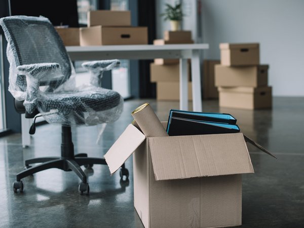 Ein eingepackter Schreibtischstuhl und mehrere Kartons in einem Büro.