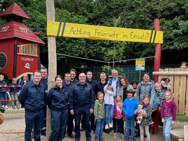Kinder und Erwachsene vor Spielgerät auf einem Spielplatz