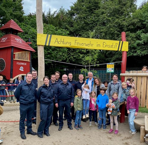 Kinder und Erwachsene vor Spielgerät auf einem Spielplatz