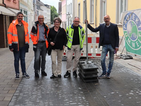Mehrere Personen stehen in der Fußgängerzone vor einem Baustellenbereich 