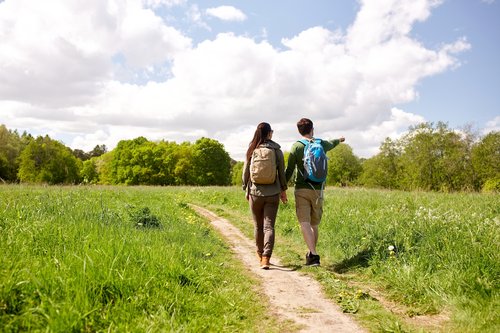 happy couple with backpacks hiking outdoors