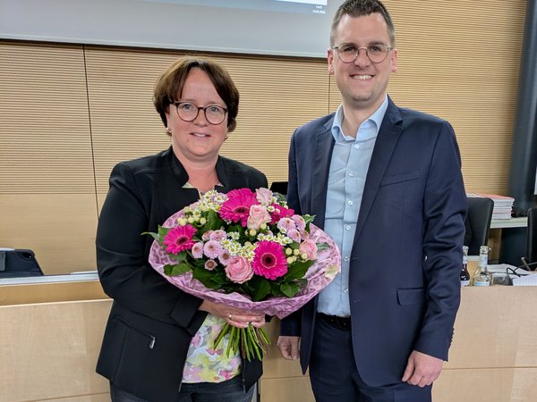 Frau mit Blumenstrauß, daneben steht ein Mann