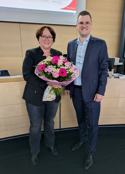 Frau mit Blumenstrauß, daneben steht ein Mann