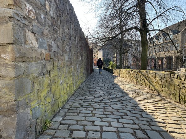 Fußweg mit Kopfsteinpflaster entlang einer Mauer 