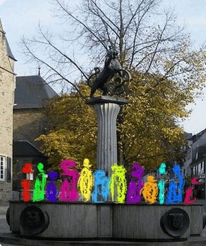 Bunte gemalte Menschen stehen auf dem Löwenbrunnen des Ratinger Marktplatzes.