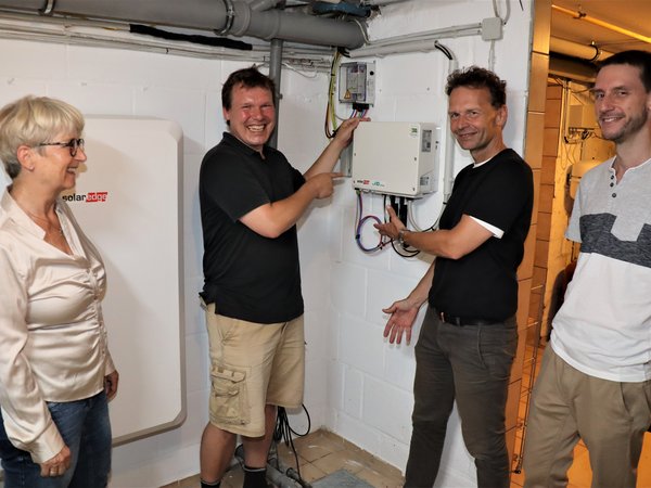 Drei Männer und eine Frau vor Solartechnikgeräten im Keller