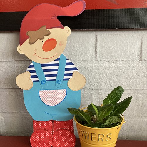 Kind mit Mütze als Pappfigur neben einem Blumentopf 