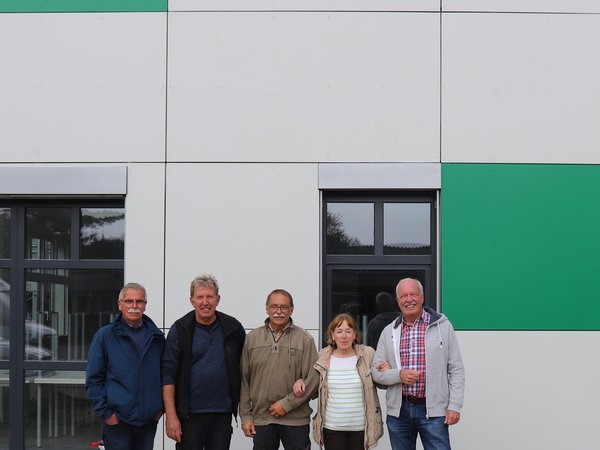 Fünf Personen vor einen weiß-grünen Gebäude